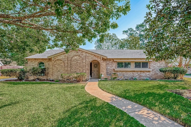 view of front of property with roof with shingles, a front lawn, and brick siding