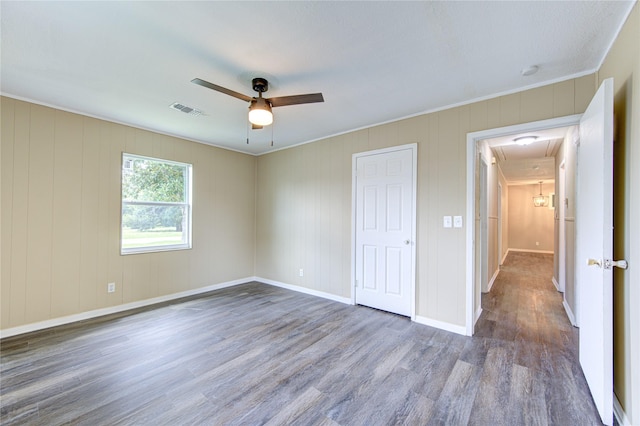 unfurnished bedroom featuring wood finished floors, visible vents, baseboards, attic access, and ceiling fan