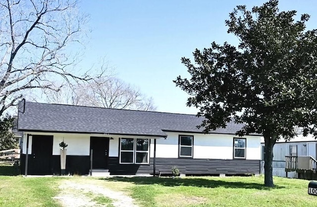 view of front of house with driveway, a front yard, and a shingled roof