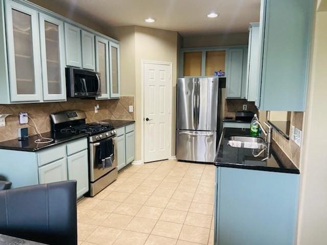 kitchen featuring appliances with stainless steel finishes, dark countertops, a sink, and tasteful backsplash