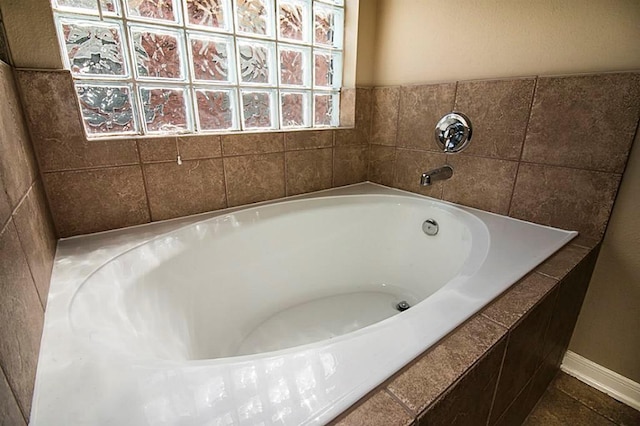 bathroom with a garden tub and baseboards