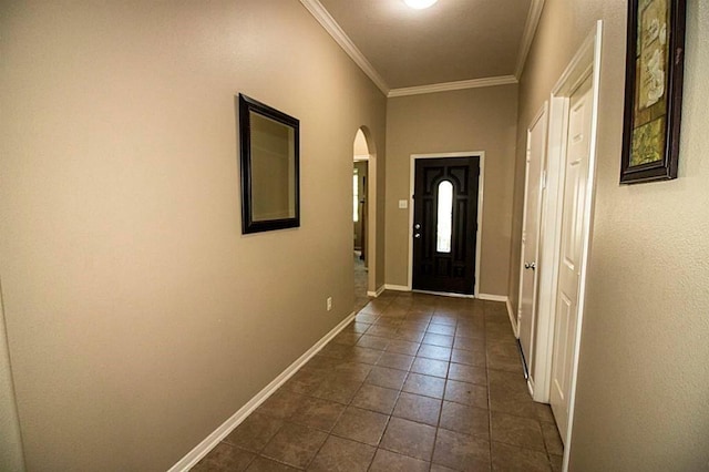 doorway to outside with baseboards, arched walkways, crown molding, and dark tile patterned flooring