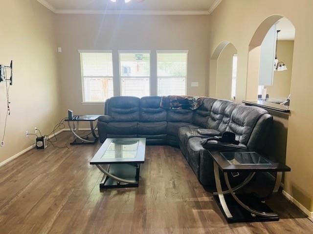 living room with arched walkways, crown molding, baseboards, and wood finished floors