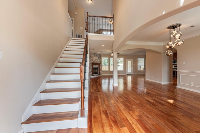 stairs with ornamental molding, a ceiling fan, a fireplace, and wood finished floors