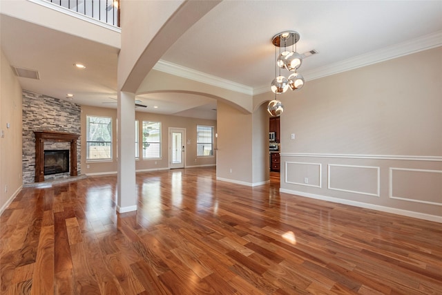 unfurnished living room with a fireplace, wood finished floors, visible vents, and crown molding