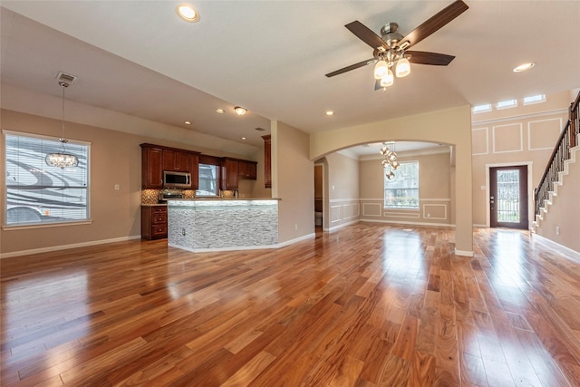 unfurnished living room featuring visible vents, a decorative wall, light wood finished floors, and stairs