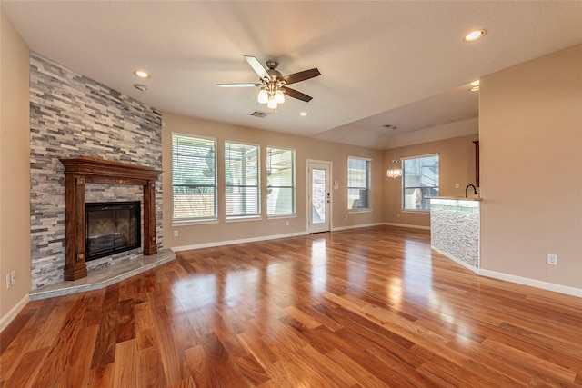 unfurnished living room featuring a fireplace, light wood-style flooring, baseboards, and ceiling fan