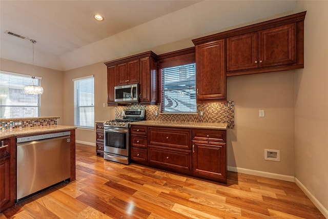 kitchen with stainless steel appliances, light wood-type flooring, baseboards, and tasteful backsplash