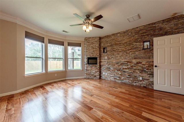 unfurnished living room with baseboards, visible vents, ceiling fan, ornamental molding, and wood finished floors