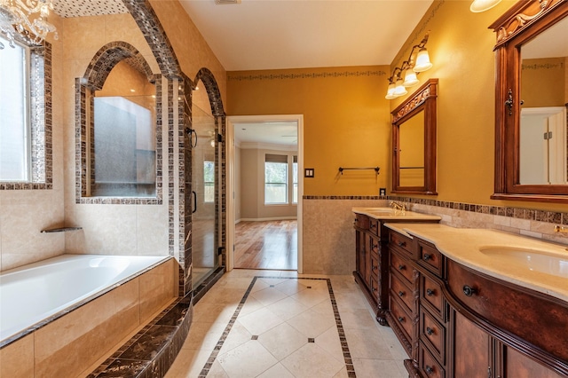 bathroom with double vanity, tile walls, wainscoting, a shower stall, and a sink