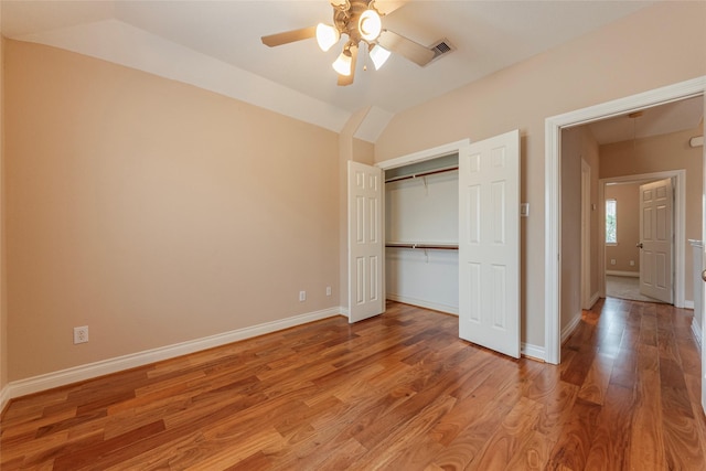 unfurnished bedroom featuring lofted ceiling, a closet, light wood-style floors, a ceiling fan, and baseboards