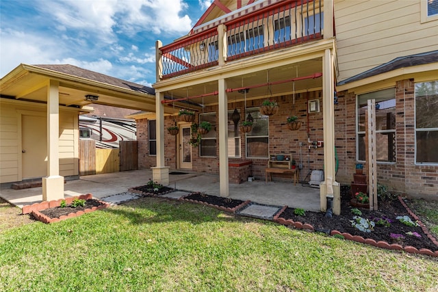 rear view of property with a yard, a patio, and brick siding