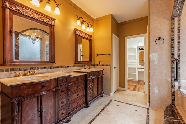 bathroom featuring a walk in closet, tile walls, double vanity, a sink, and tile patterned flooring