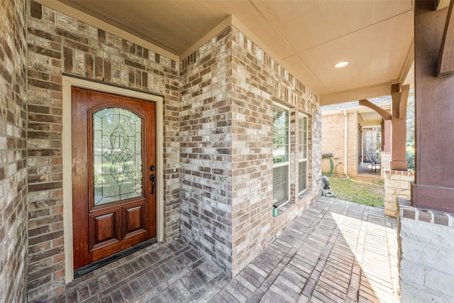 doorway to property featuring brick siding and a porch