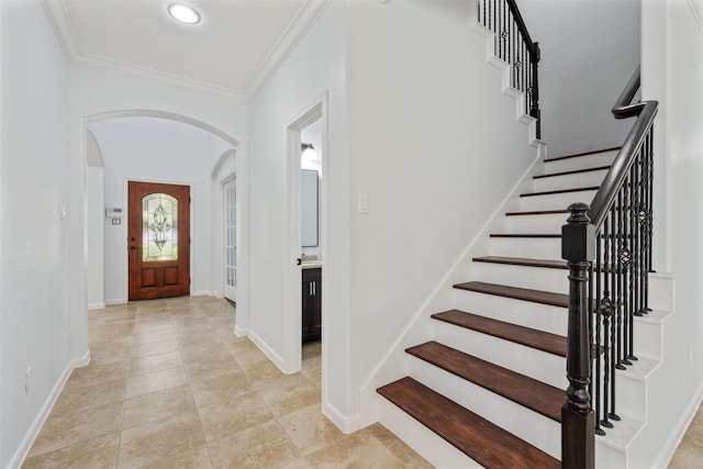 entryway featuring arched walkways, baseboards, light tile patterned flooring, and crown molding