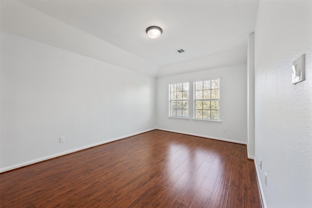 unfurnished room with visible vents, dark wood finished floors, and baseboards