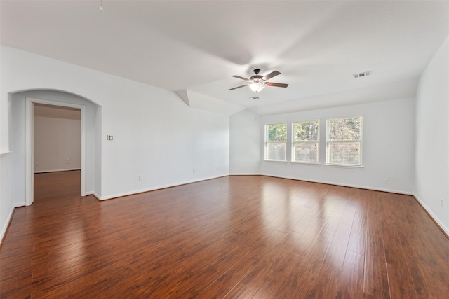 spare room featuring baseboards, visible vents, arched walkways, ceiling fan, and dark wood-type flooring