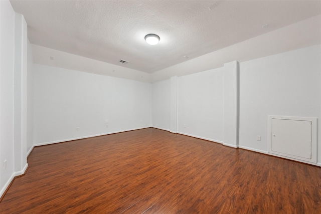 unfurnished room featuring baseboards, a textured ceiling, visible vents, and wood finished floors