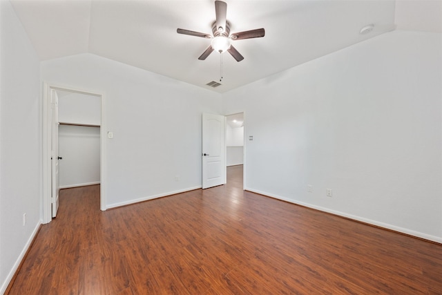 unfurnished bedroom with lofted ceiling, dark wood-style floors, a spacious closet, and visible vents