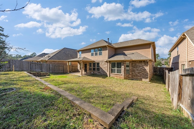 back of house with a yard, brick siding, a patio, and a fenced backyard