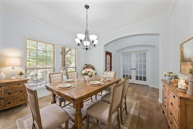 dining room featuring baseboards, arched walkways, ornamental molding, wood finished floors, and french doors