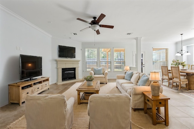 living room with crown molding, light tile patterned floors, visible vents, a glass covered fireplace, and ceiling fan with notable chandelier