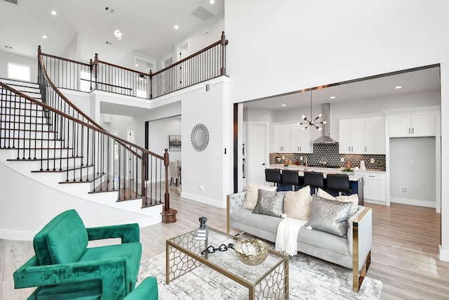 living room featuring light wood finished floors, baseboards, stairway, and a chandelier