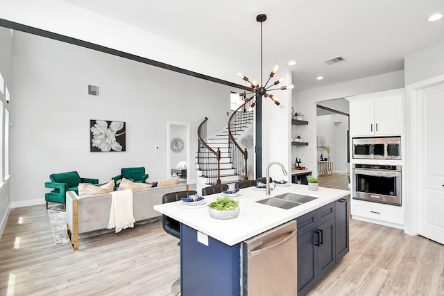 kitchen featuring stainless steel appliances, a sink, visible vents, light countertops, and an island with sink