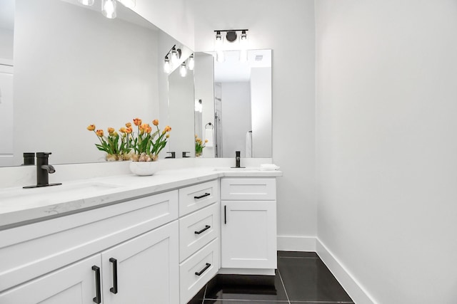 bathroom with tile patterned floors, a sink, baseboards, and double vanity