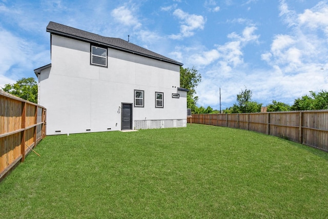 back of property with a fenced backyard, a yard, and stucco siding