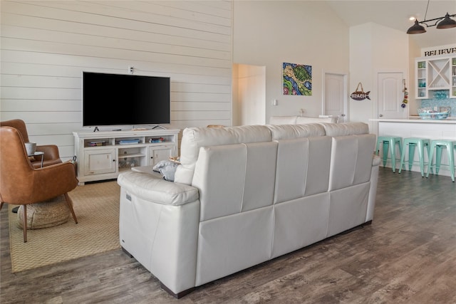 living room featuring high vaulted ceiling, wood walls, and wood finished floors