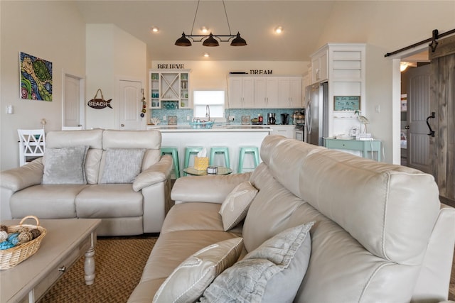 living area featuring lofted ceiling, a barn door, and recessed lighting