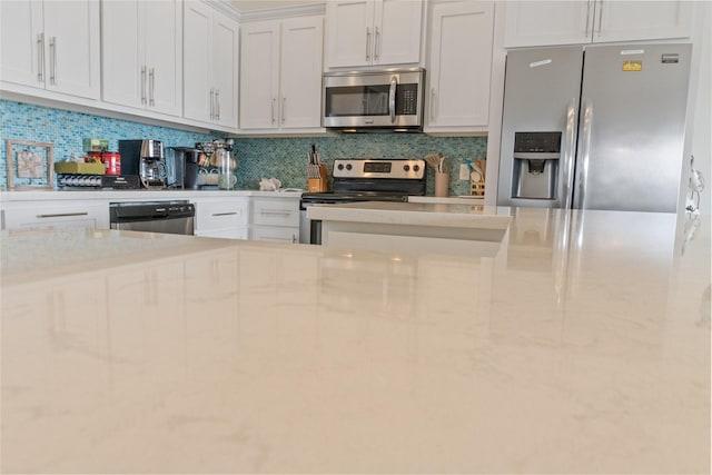 kitchen with stainless steel appliances, white cabinetry, backsplash, and light stone counters