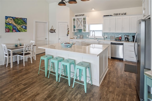 kitchen featuring stainless steel appliances, tasteful backsplash, light countertops, white cabinetry, and a sink