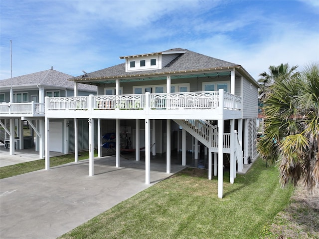 back of house with a porch, a shingled roof, a yard, concrete driveway, and a carport