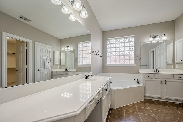 bathroom featuring a garden tub, tile patterned flooring, two vanities, a sink, and visible vents