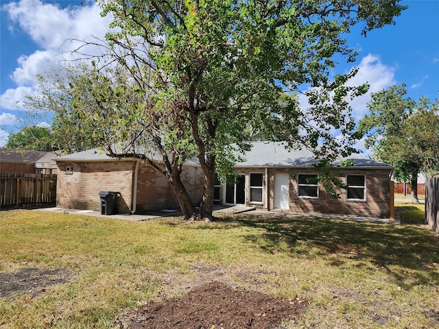 rear view of house featuring a yard, a patio area, fence, and brick siding