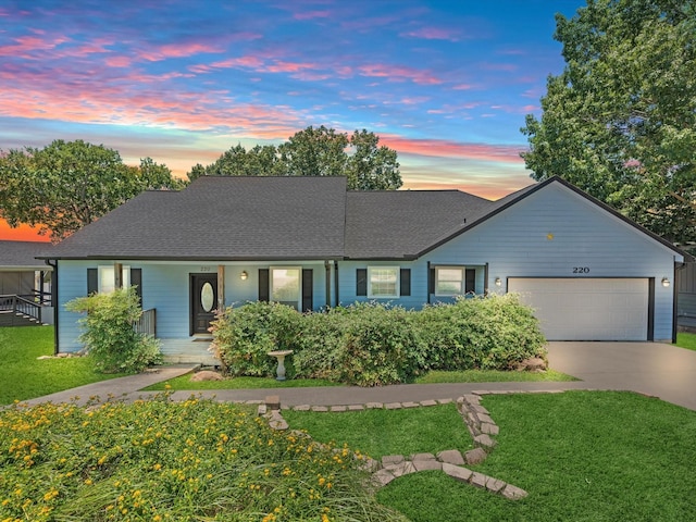 ranch-style house featuring a garage, roof with shingles, concrete driveway, and a front yard