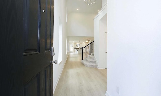 entryway with light wood finished floors, stairs, baseboards, and a ceiling fan