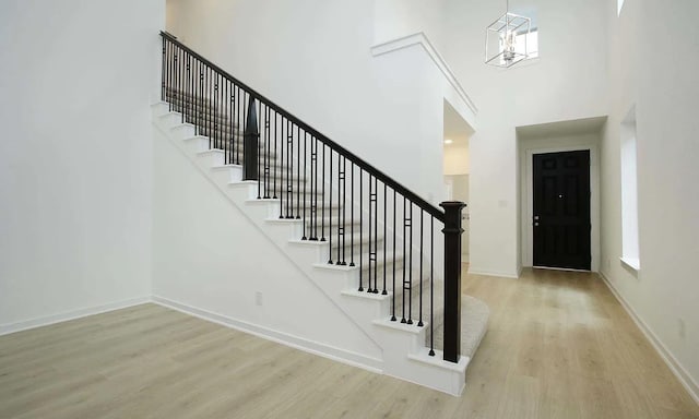 entrance foyer with a high ceiling, stairway, wood finished floors, and baseboards