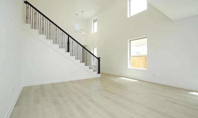 unfurnished living room with baseboards, stairway, and wood finished floors