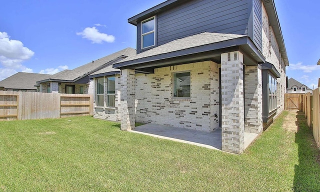 rear view of property with a yard, a patio, stone siding, and a fenced backyard