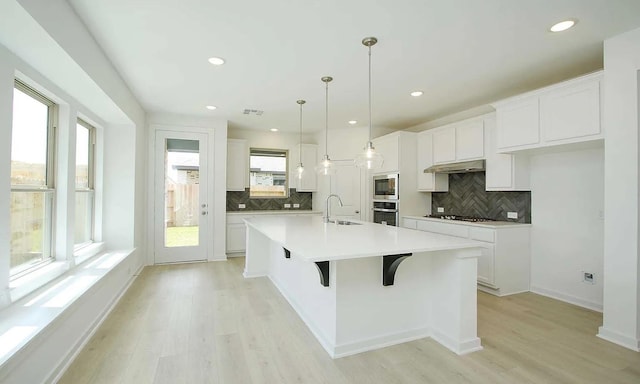 kitchen featuring appliances with stainless steel finishes, light wood-style floors, white cabinetry, and a sink