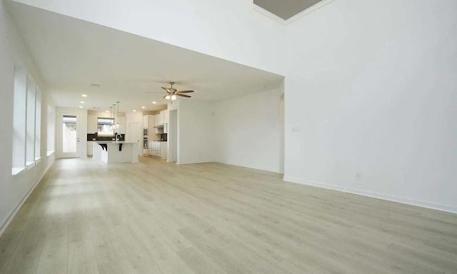 unfurnished living room with recessed lighting, a sink, a ceiling fan, baseboards, and light wood finished floors