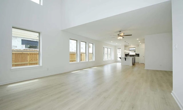 unfurnished living room featuring light wood finished floors, baseboards, a ceiling fan, and recessed lighting