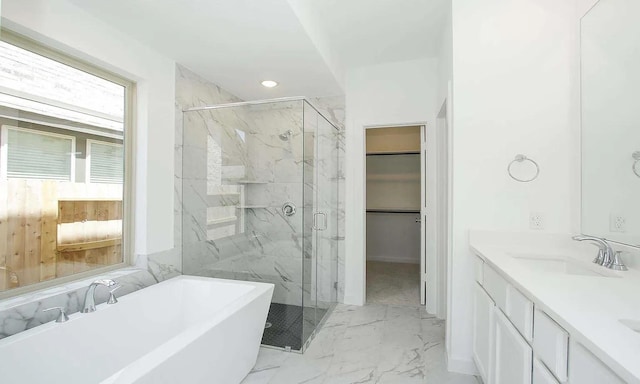 full bath with a marble finish shower, marble finish floor, a walk in closet, a freestanding bath, and a sink