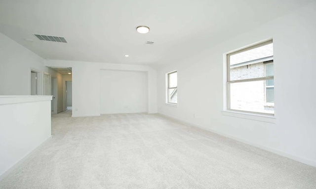 spare room featuring light colored carpet and visible vents