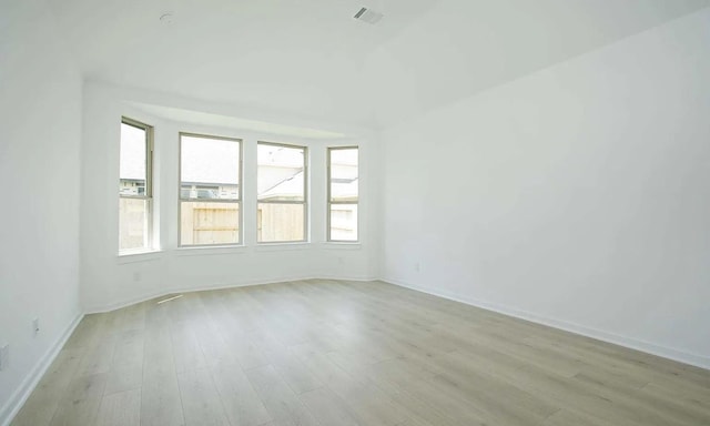 spare room featuring light wood-type flooring, visible vents, and baseboards