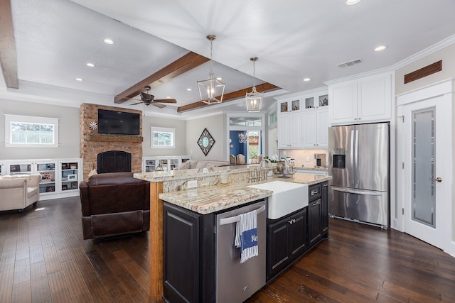 kitchen featuring appliances with stainless steel finishes, open floor plan, dark wood-style flooring, white cabinetry, and a sink