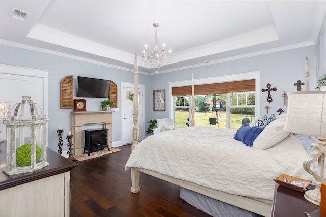 bedroom with a chandelier, dark wood-type flooring, visible vents, a raised ceiling, and a wood stove